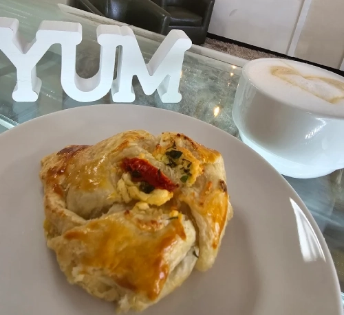 Savory puff pastry filled with vegetables and egg, served with a cappuccino.