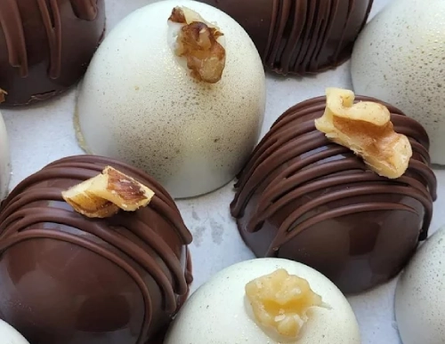 Assorted dome-shaped chocolate truffles topped with nuts.