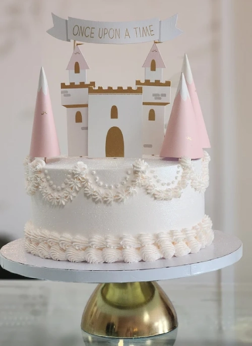 Elegant princess-themed cake with castle topper and pink towers.